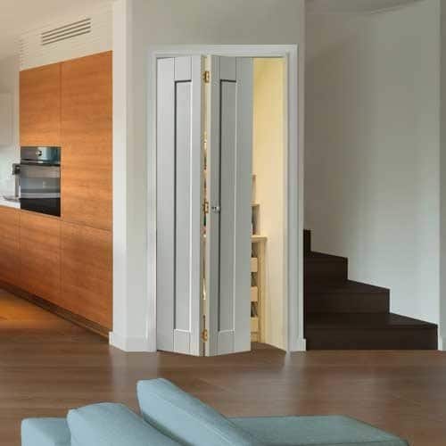 A white bifold door half open and hung on a pantry attached to a kitchen